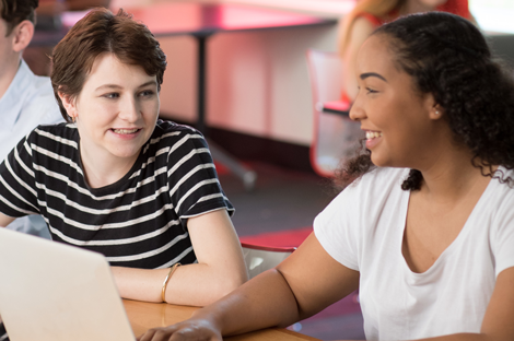 Two students sitting at a desk with a laptop