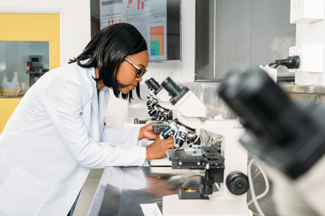 Woman in lab coat looking into microscope