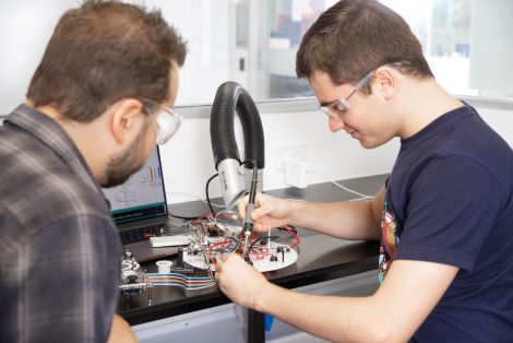 Two males working on soldering electronics in the QCA design studios