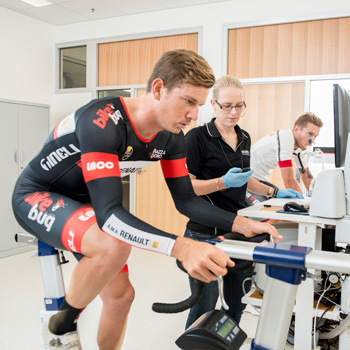 exercise scientist checking data for a cyclist on a stationary bike