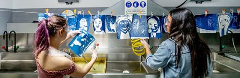 Two students hanging artwork to dry