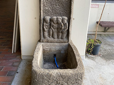 a stone sculputure with four human figues above a squared well