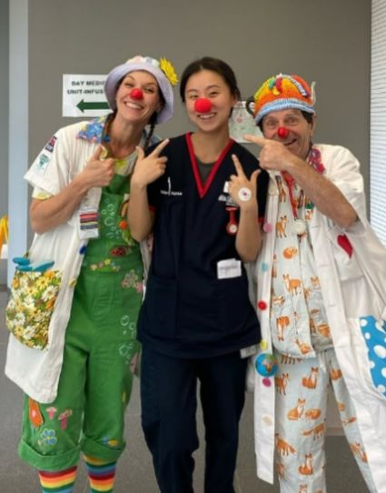 Nursing student smiling with two clown doctors. 