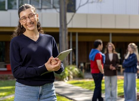 Female student holding a laptop standing outside Griffith university