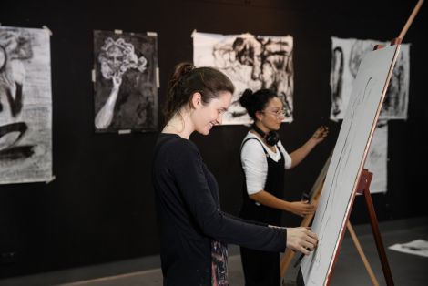 Two students draw on easels in the QCA drawing studio