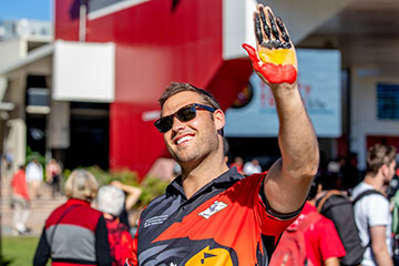 A student wearing sunglasses waving a painted hand