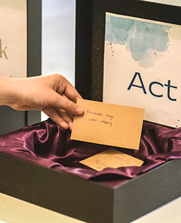 hand picking a notice saying 'reusable bags when shopping' out of a suggestion box labelled 'act'