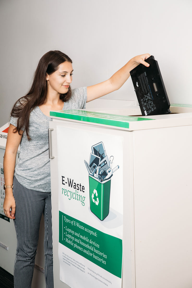 Woman putting laptop in e-waste bin