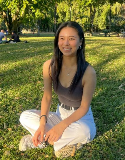 Korean student at park sitting on grass.