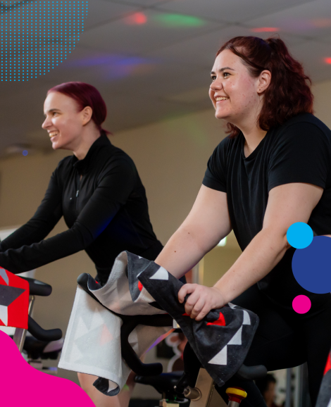 two women riding exercise bikes