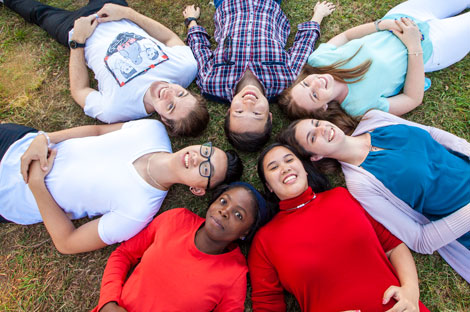 Group of students lying down in a circle looking up 