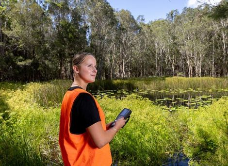 Female student testing water quality in a river