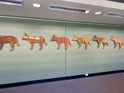 a wall art made up of individual dog sculptures spanning across the darkish-green wall