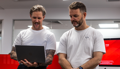 Two people in a classroom or office setting reviewing information together on a laptop, supporting hands-on learning and skills development.