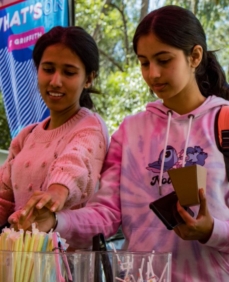 two students picking lollies from a jar