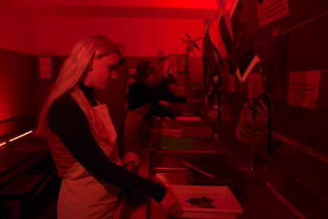 Red lit student developing images in the QCA darkroom