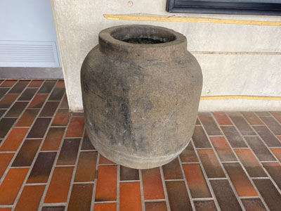 a brown stone jar on the brick floor tiles