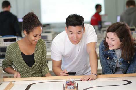 Two women and one man leaning over a desk