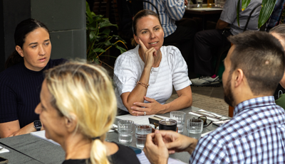 Small group seated around a table in discussion, collaborating in an informal setting that reflects community and partnership-building.