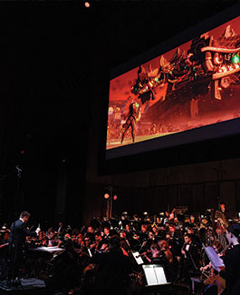 orchestra with film playing above