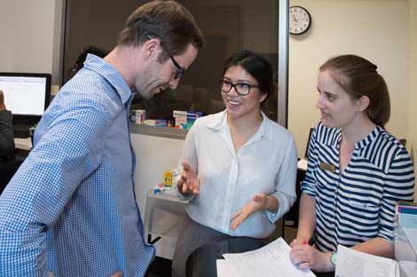 Two women anf one man standing in a lab talking