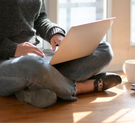 image of a female sitting down near a window with a laptop in her lap