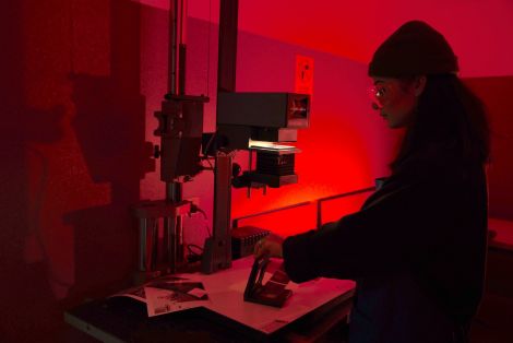 Red lit student developing images in the QCA darkroom