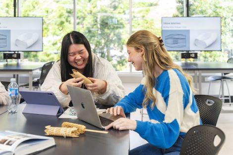 Two people sitting at laptops working on a design piece