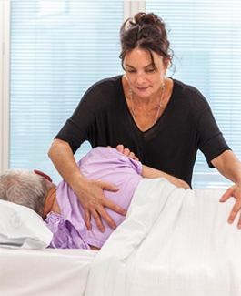 A nurse helping a male patient rolling to the side