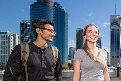Two students walking through Brisbane, Queensland with high rise buildings behind them