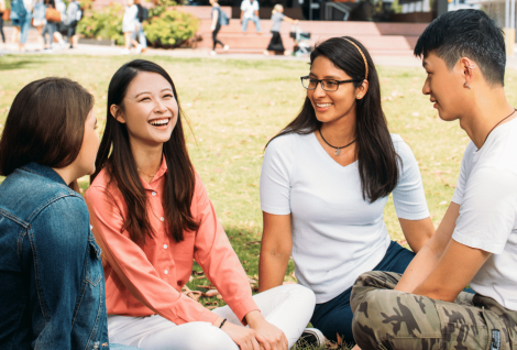 Three students sitting on the grass on campus