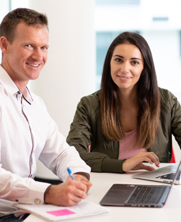 Two people at desk with laptops