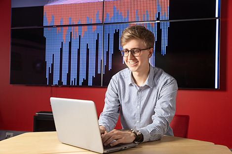 Person typing on laptop in front of projection of a graph