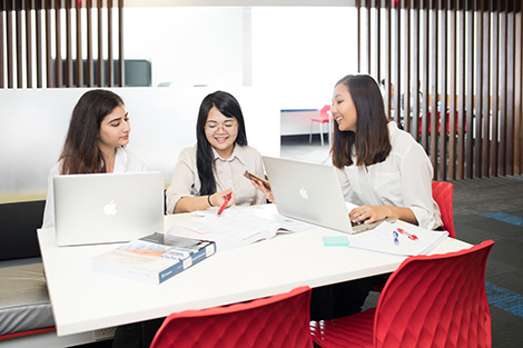 Three people with laptops sitting in a library