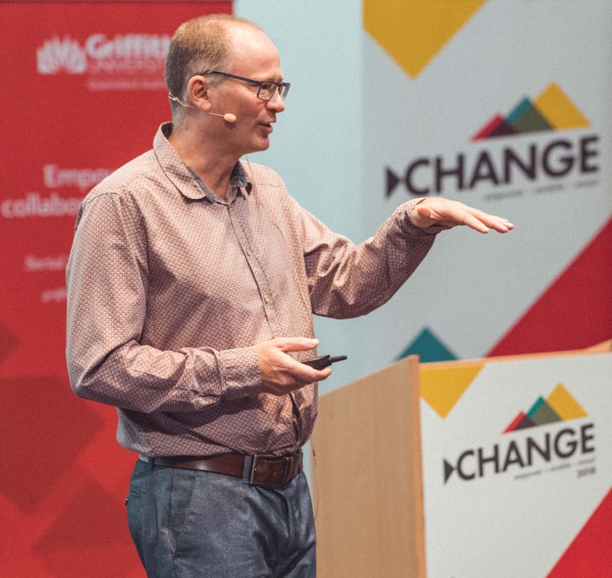 Someone speaking on stage to an audience with a Change conference banner in the background