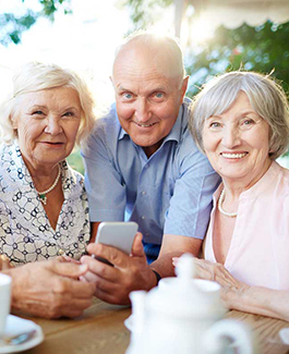 two women and one man looking at a mobile phone 