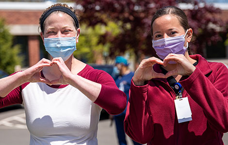Two nurses holding their hands in the shape of hearts