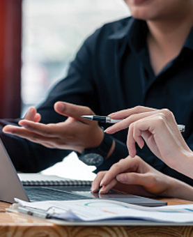 four hands working on laptops