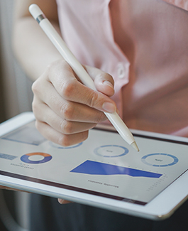 person holding stylus over iPad with graphs displayed