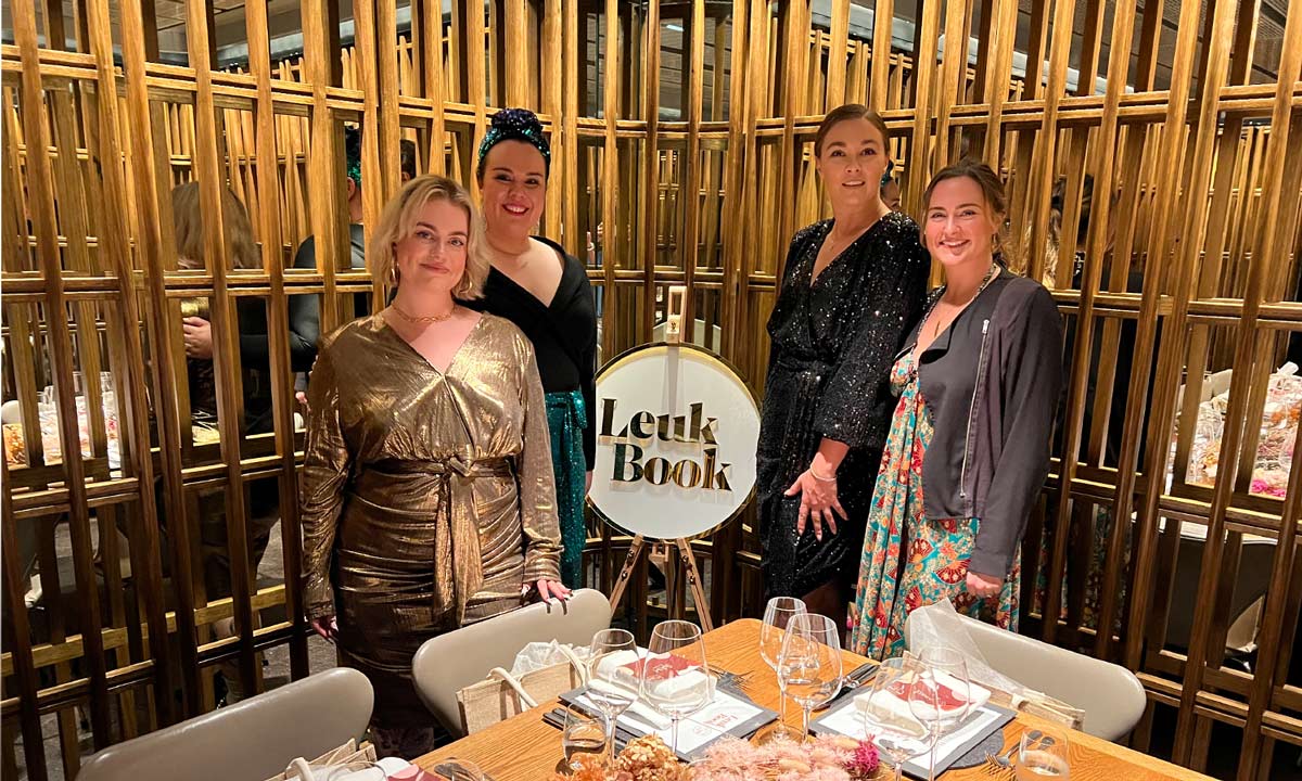 four females posing in front of LeukBook sign at LB fashion week dinner