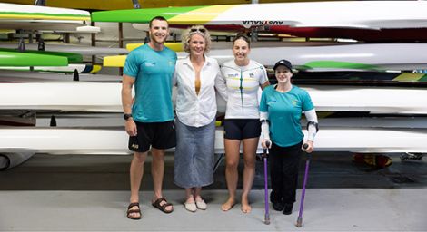 Athletes standing in front of a stacked kayaks