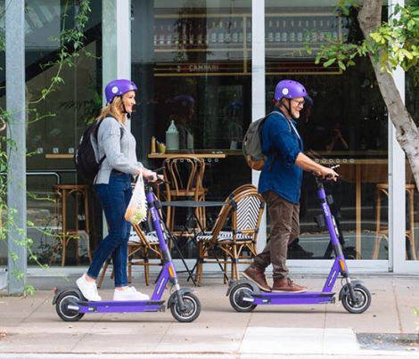 man and woman riding e-scooters