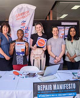 The crew of the repair cafe in front of a pull up banner